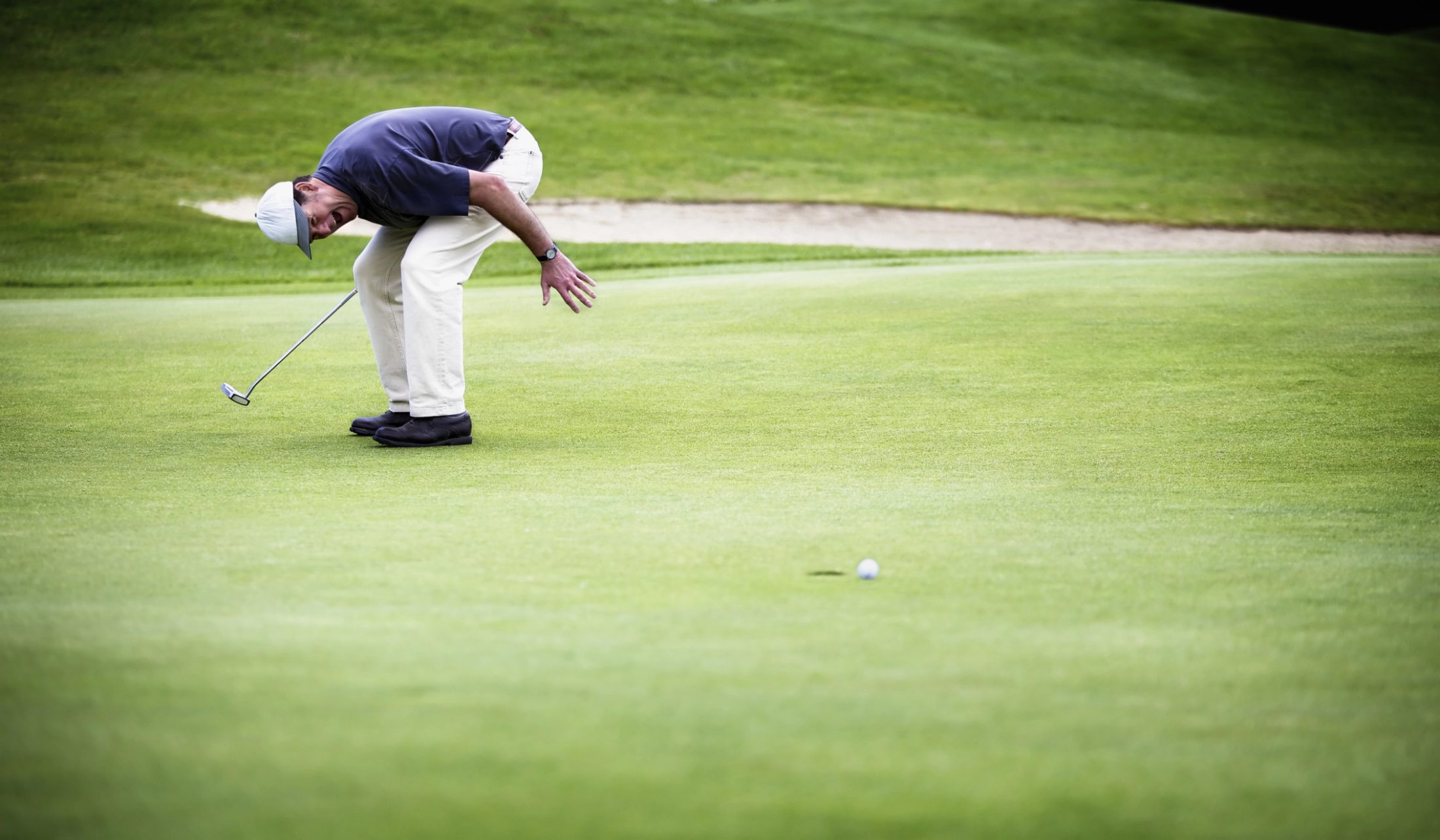 A golfer watches a putt roll toward the hole